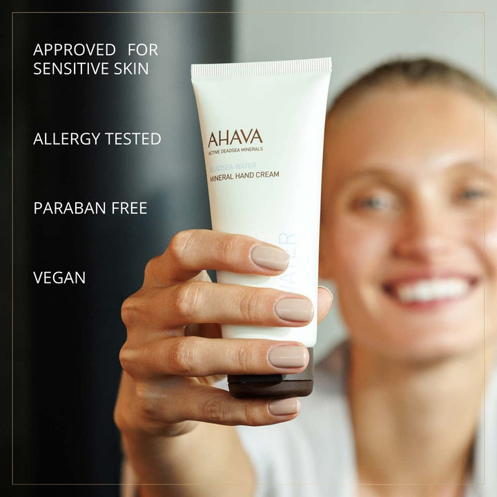 Person holding a tube of Ahava hand cream with product features listed on the left.