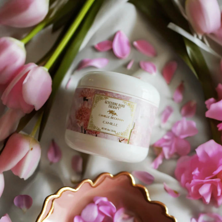 Jar of cream with a floral label on a surface with pink flowers and petals