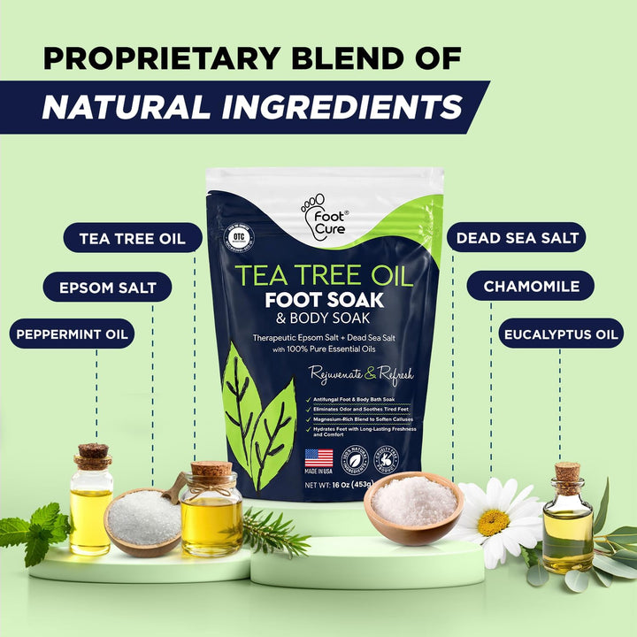 A retail display for Foot Cure Tea Tree Oil & Body Soak. The main product is a dark navy blue and white pouch with green accents, surrounded by its key ingredients (tea tree oil, epsom salt, peppermint oil, dead sea salt, chamomile, eucalyptus oil) arranged on pedestals against a light green background with text overlays.