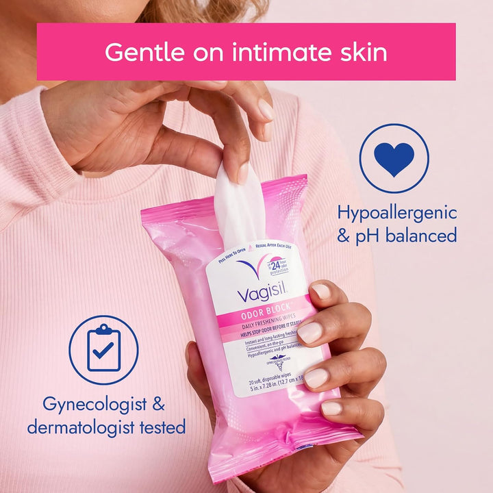 A person in a light pink top holds a Vagisil Odor Eliminator wipe packet against a pale pink background with marketing text and icons about gentle use, hypoallergenic formula, and dermatologist testing.