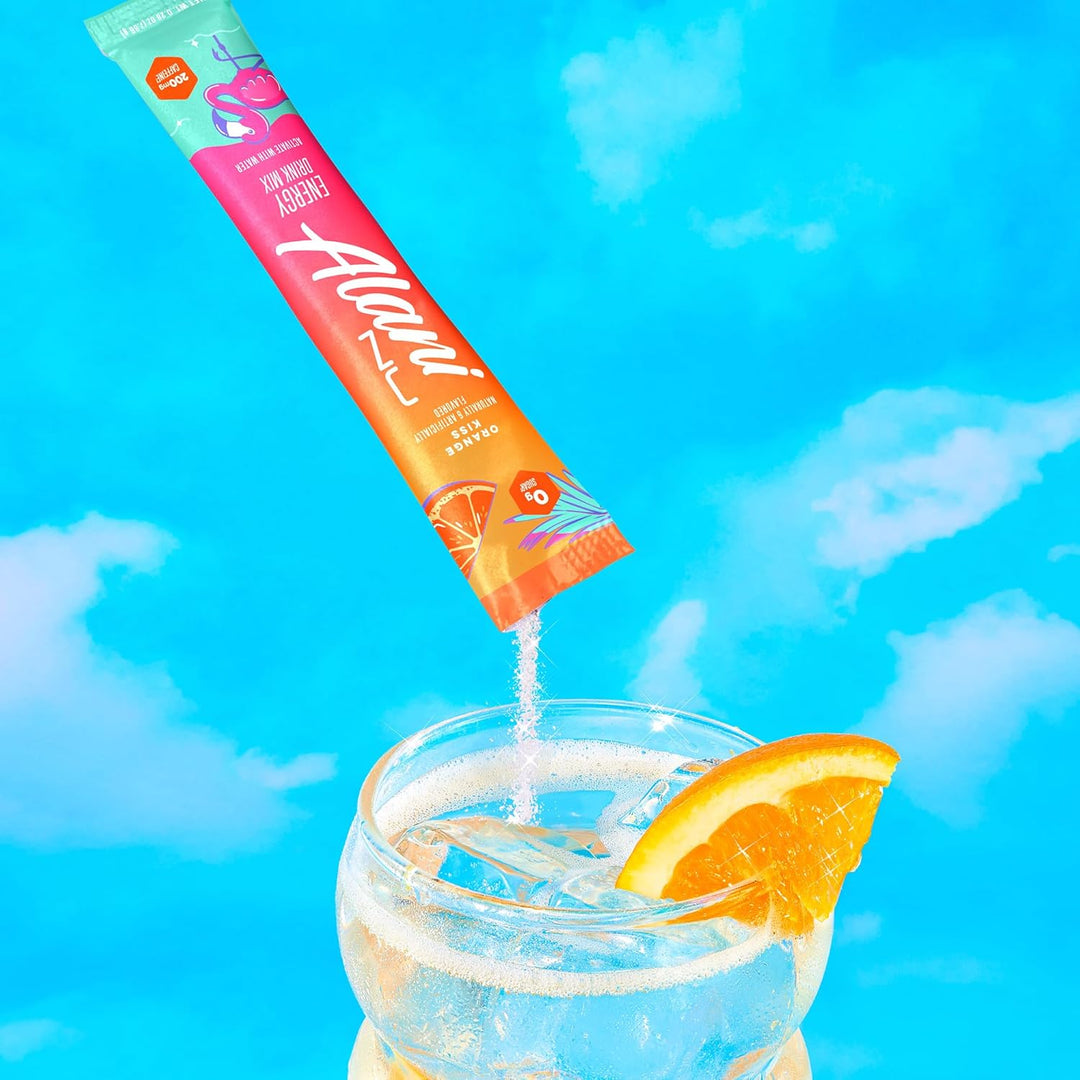 Alani Nu supplement stick pack being poured into a glass of water with an orange slice against a blue sky background