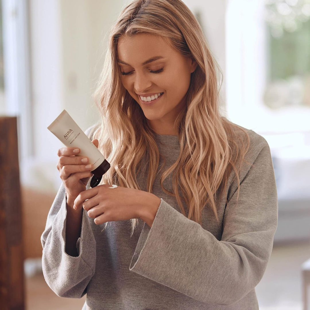 Woman holding a hair product in a bright indoor setting