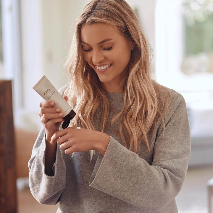 Woman holding a hair product in a bright indoor setting